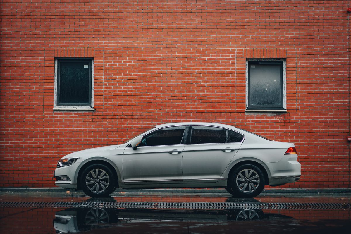 Fehér Volkswagen Passat téglafal előtt